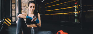 girl using phone next to boxing ring