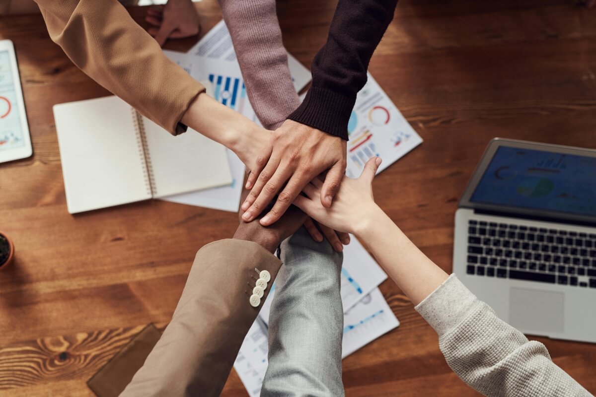 People putting their hands on top of each other in a display of group camaraderie.